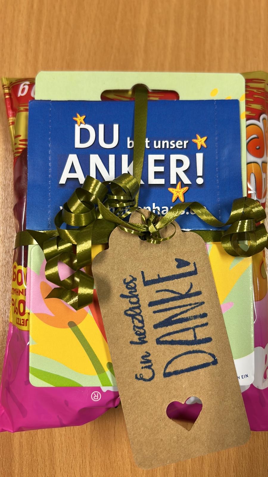 Geschenkverpackung mit grünem Geschenkband und braunem Anhänger mit der Aufschrift 'Ein herzliches DANKE'